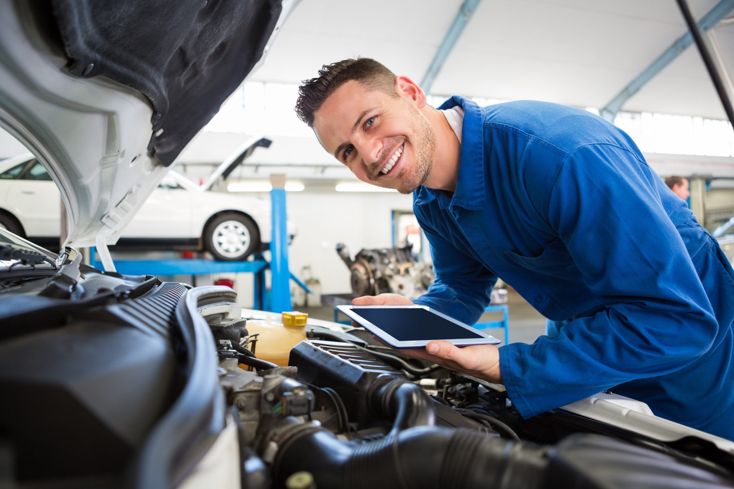 Automotive technician inspecting a vehicle engine in a service center.