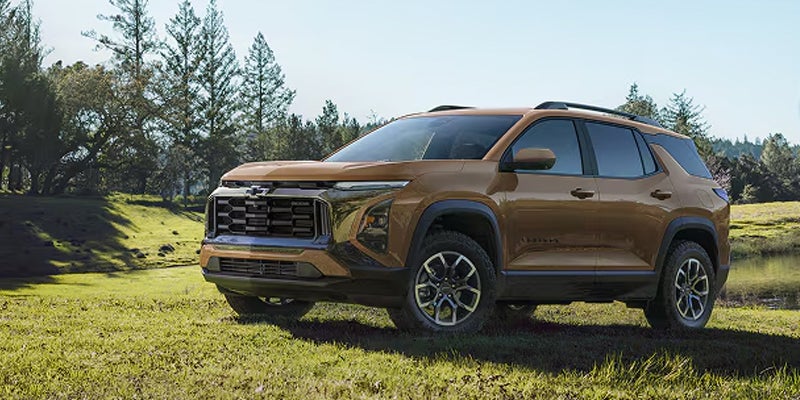 2027 Chevy Equinox SUV parked on a grassy field surrounded by trees.